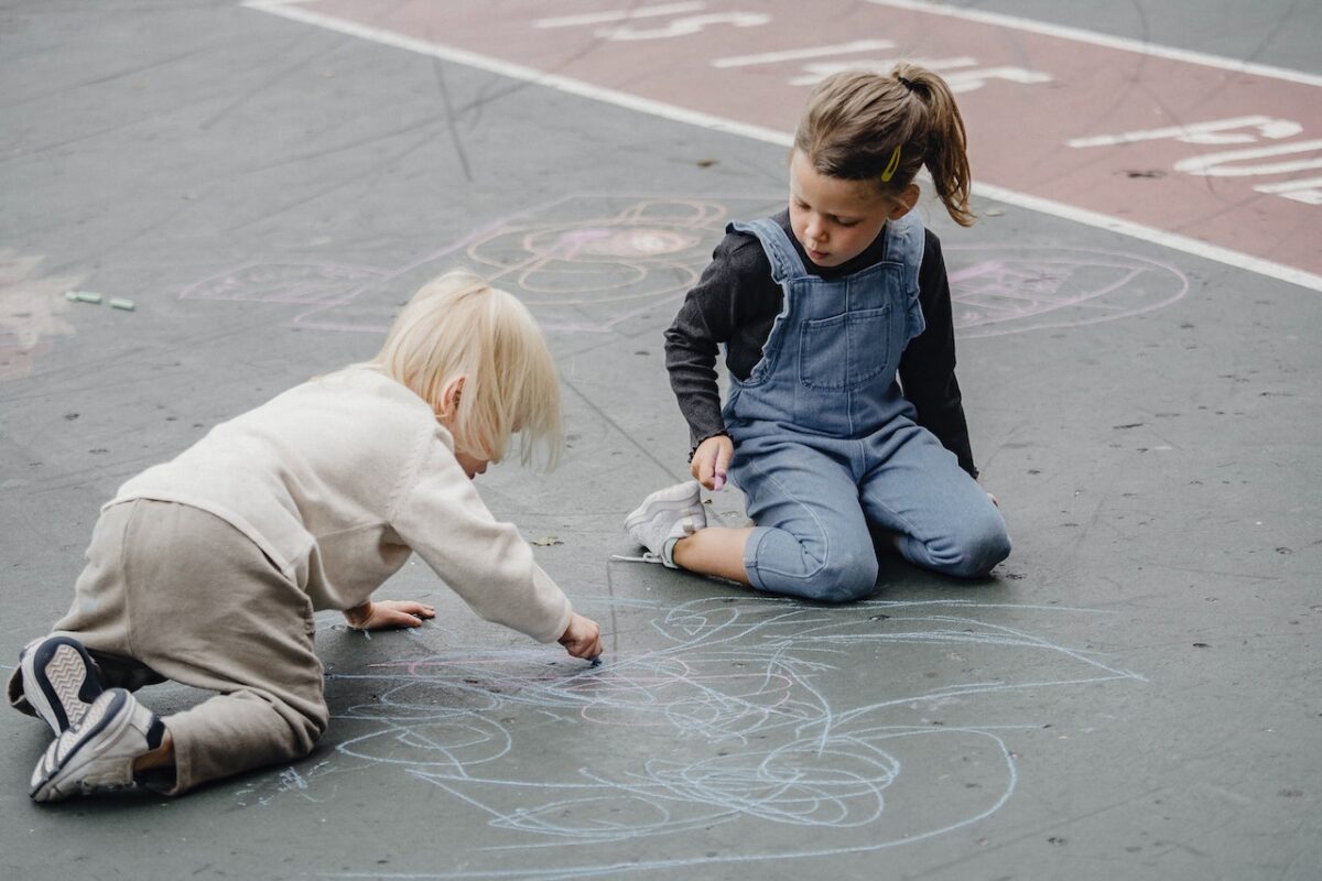 Children playing with chalk and drawing on ground symbolic of how divorce affects children.