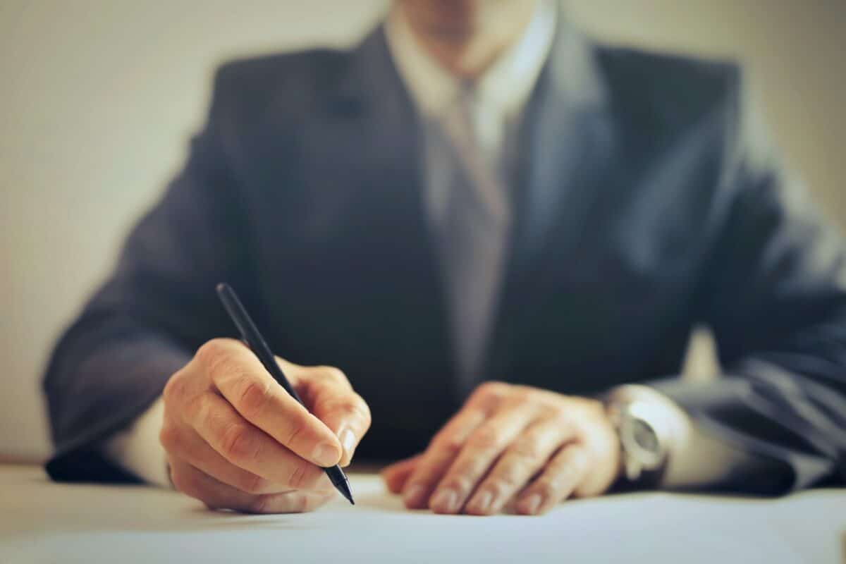 Man in suit and tie sigiing documents adhering to proper court etiquette