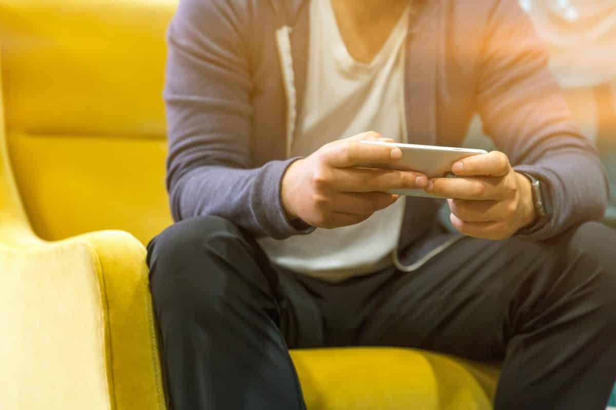 Man holding mobile phone and sitting on yellow sofa