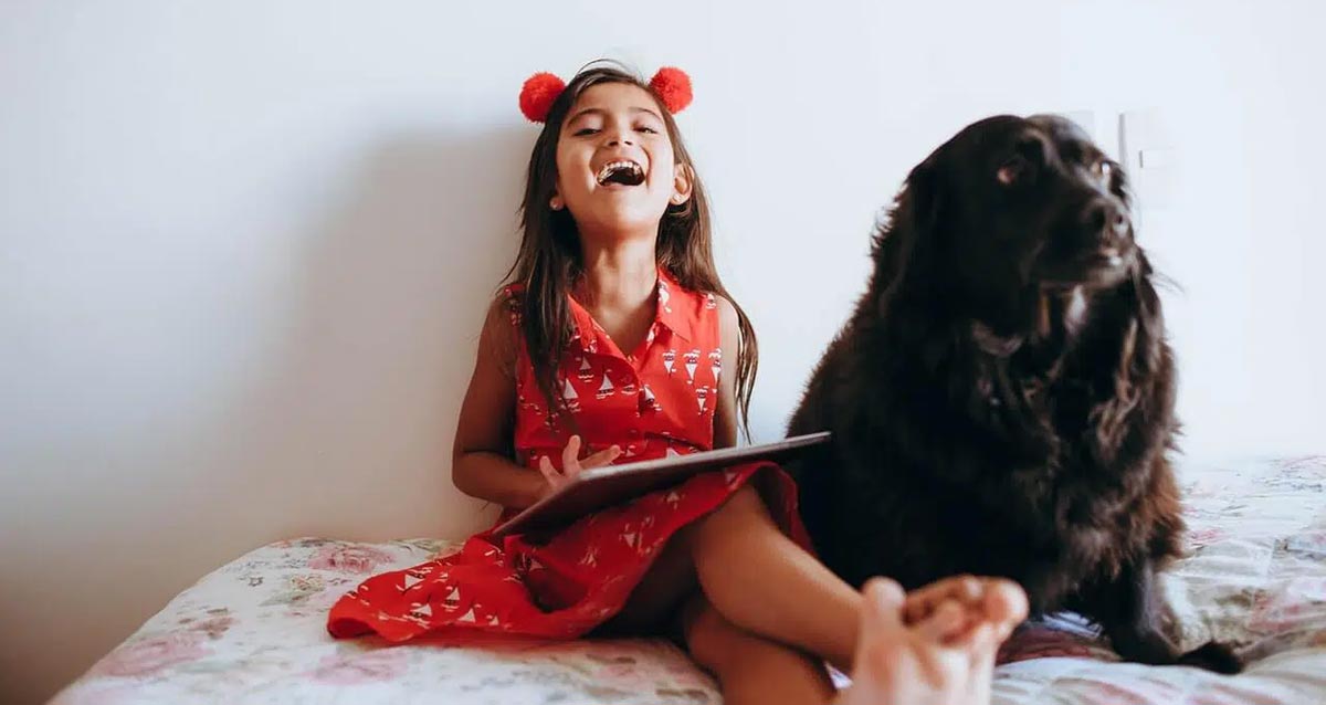 Young girl laughing with happiness next to pet dog custody.