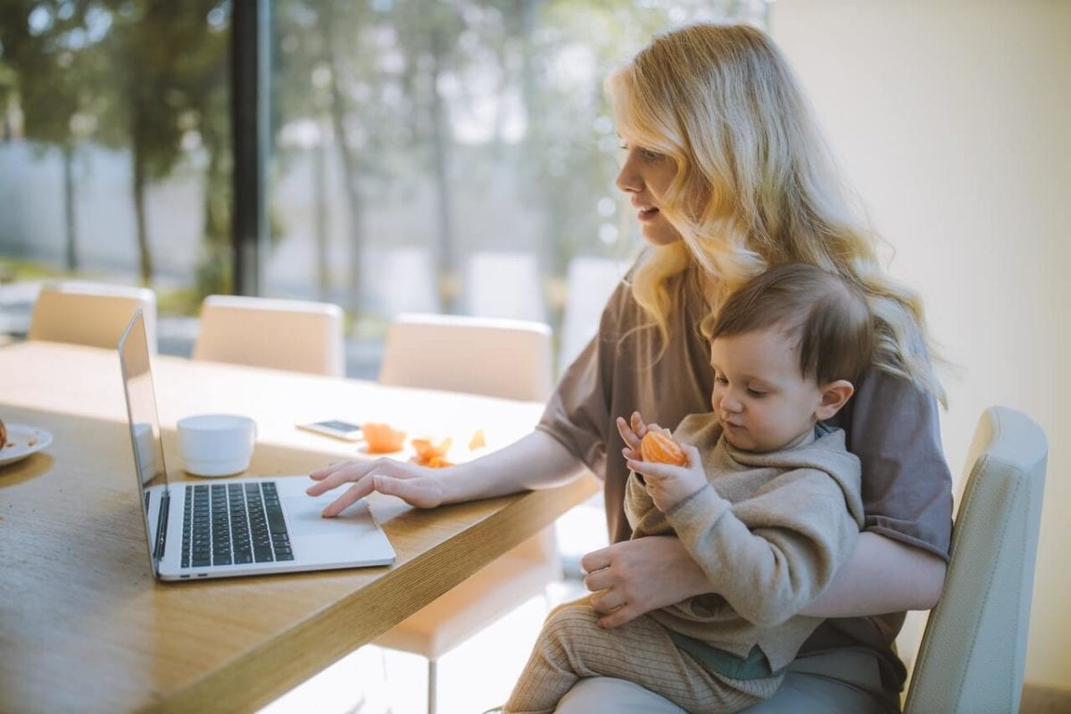 Mother working on laptop holding a baby