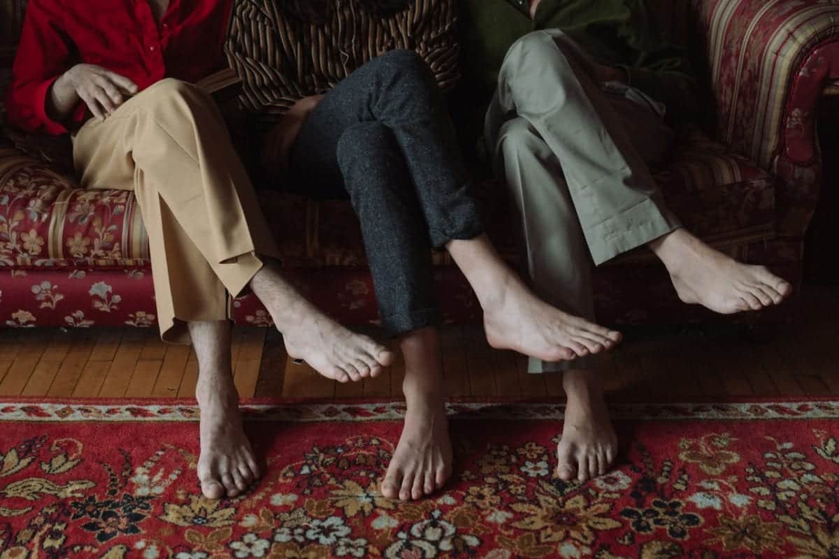 Three pairs of feet side by side implying throuple relationships