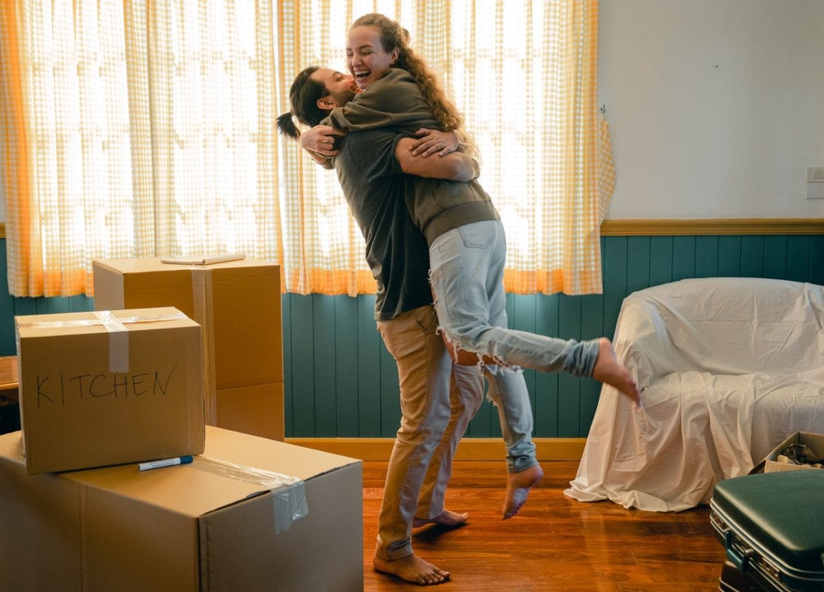 Happy couple with prenup benefits unpacking boxes in new home