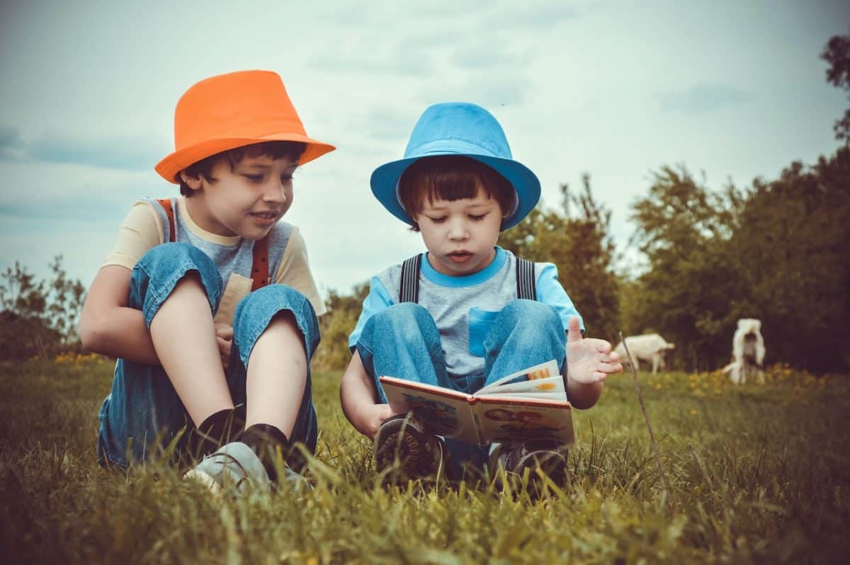 Two children reading in a meadow with bucket hats under a great example of good parenting arrangements and agreements
