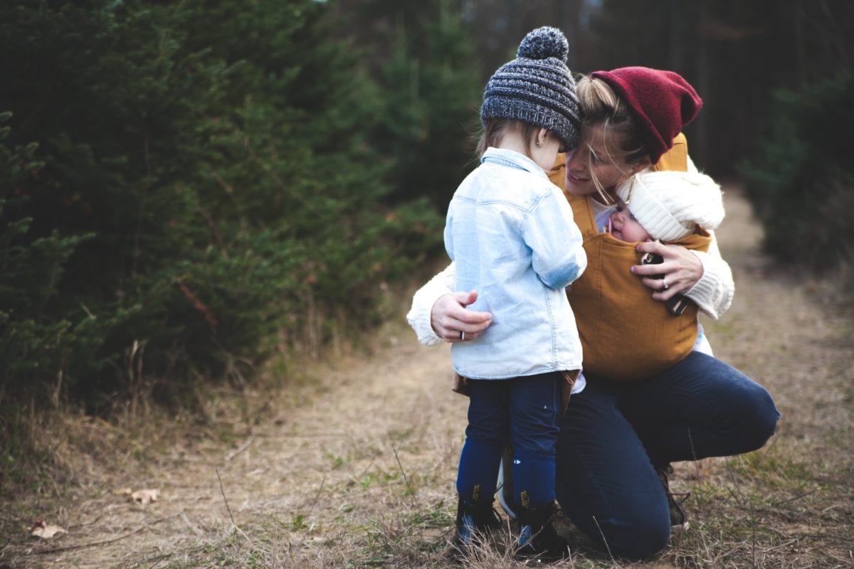 Parent is hugging children outdoors after experiencing domestic violence and family law